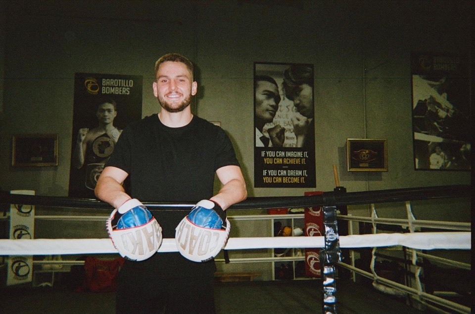 Coach Baki holding focus mitts inside a boxing ring